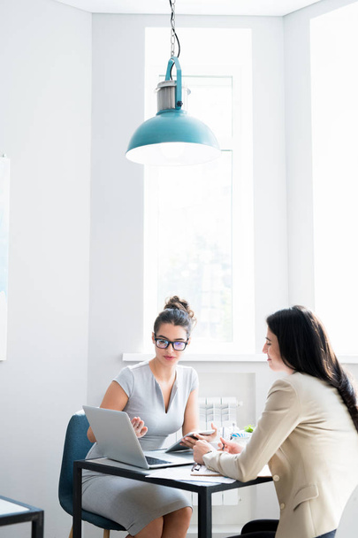 Portrait de deux belles jeunes femmes utilisant un ordinateur portable à la table dans un café tout en travaillant pendant une réunion d'affaires, copier l'espace
 - Photo, image