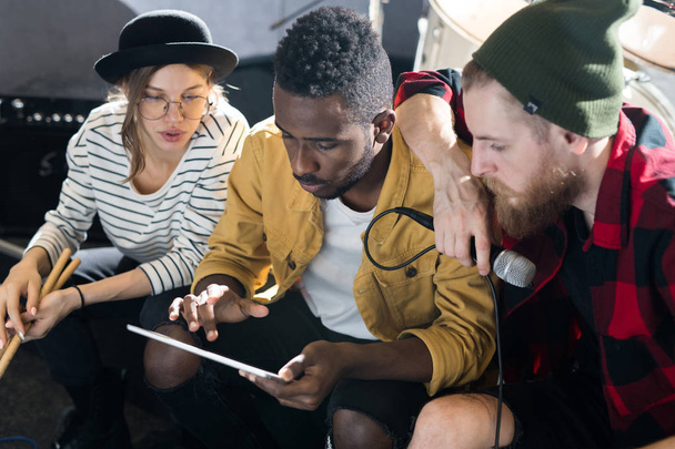 Retrato de tres jóvenes usando tableta digital mientras escribían música en el ensayo de la banda
 - Foto, Imagen