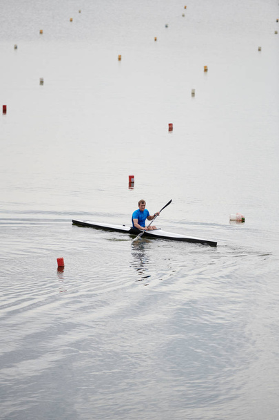 Молодой каякер учится плавать на каяке по озеру
 - Фото, изображение