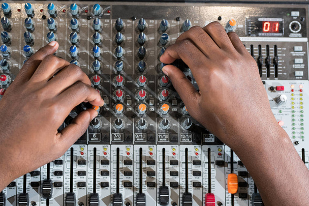 Primer plano de manos masculinas que cambian los controladores en la consola de mezcla de sonido durante la grabación de música en el estudio, espacio de copia
 - Foto, imagen