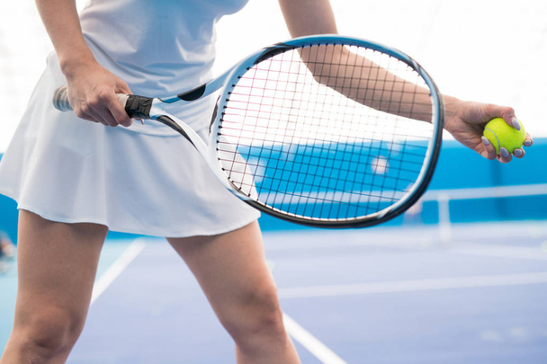 Fechamento de meio de seção de mulher jovem irreconhecível segurando raquete enquanto joga tênis no tribunal interno, espaço de cópia
 - Foto, Imagem