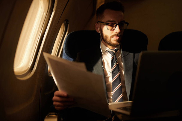 Портрет успешного молодого бизнесмена, работающего в тусклом самолете, наслаждающегося полетом первого класса, копировальным пространством
 - Фото, изображение