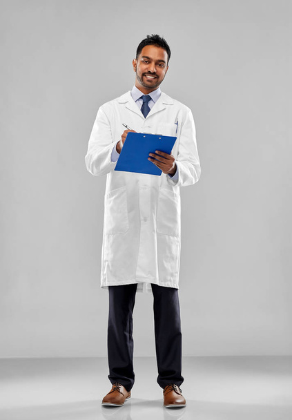 smiling indian doctor or scientist with clipboard - Foto, Imagen