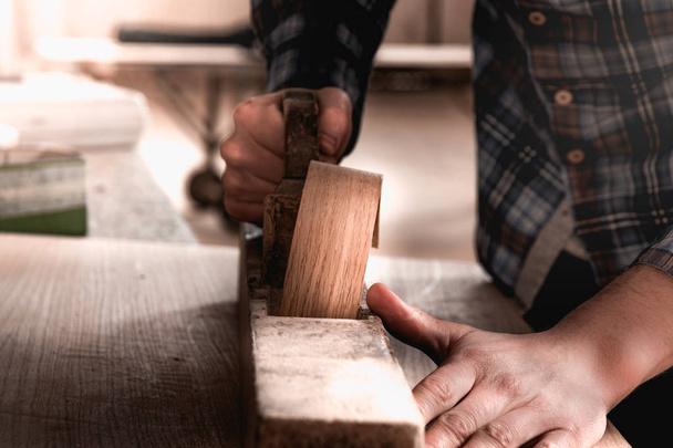 Vintage carpenter working on wood using wood retro vintage old ancient planer. Workshop background. - Photo, Image