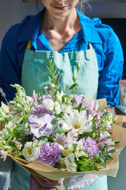 Портрет неузнаваемой флористки, держащей красивый букет, освещенный солнечным светом, в цветочном магазине.
 - Фото, изображение