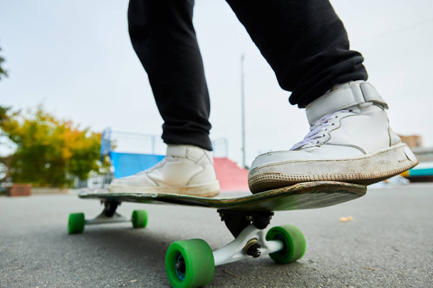 Close up of unrecognizable teenager riding longboard outdoors in skateboarding park, copy space - Foto, Imagen