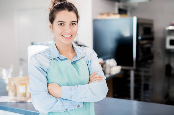 Waist up portrait of confident young woman smiling happily while standing with arms crossed in small shop and looking at camera, copy space - Photo, Image