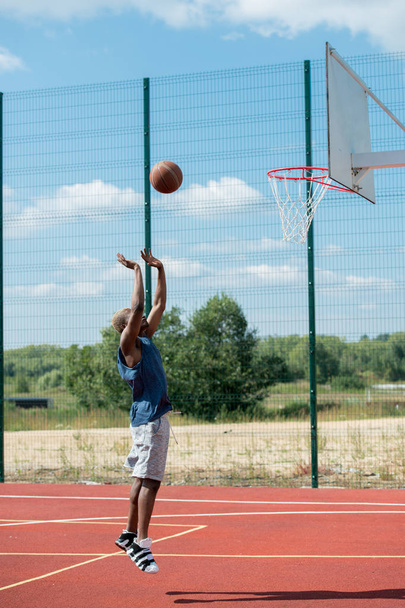 Seitenansicht Action-Aufnahme eines Afrikaners, der im Basketballfeld springt und Punkte erzielt, Kopierraum - Foto, Bild