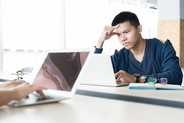 Серьезный сконцентрированный молодой азиатский программист сосредоточился на работе за столом и установке установки для ноутбука на открытом пространстве
 - Фото, изображение