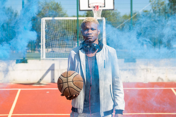 Талії до портрет сучасної африканської людини постановки з баскетбольної кулі в спортивному дворі покриті дим, копіювати простір - Фото, зображення