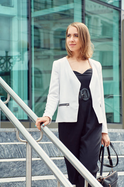 outdoor portrait of a stylish woman in business suit with ladies handbag - Фото, изображение