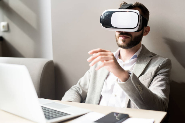Jovem trabalhador de escritório vestindo óculos de realidade virtual trabalhando em seu local de trabalho no escritório
 - Foto, Imagem