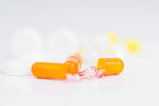 Close up shot of opened gelatin capsule with drug substance spilling on white background, medication concept - Photo, Image