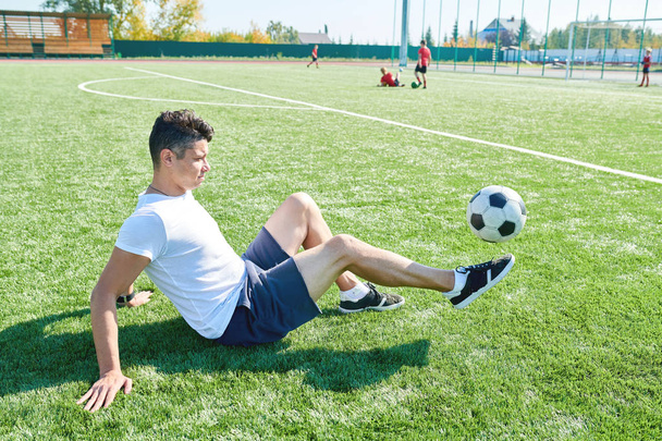 Full length portrait of Latin-American football player kicking ball in outdoor field practicing before match, copy space - Photo, Image