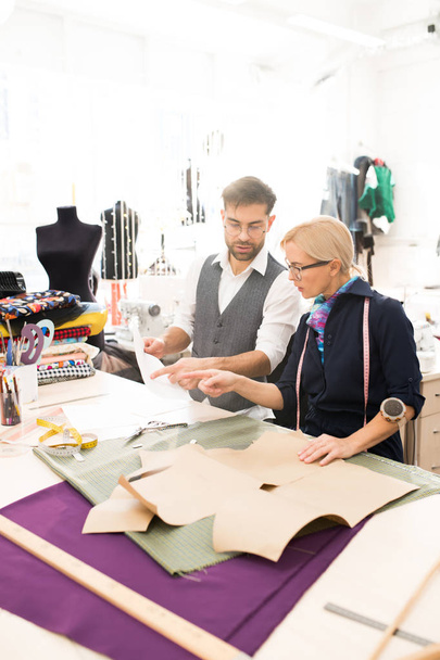 Portret pod wysokim kątem dwóch projektantów mody pracujących na ubraniach stojąc przy stole w warsztacie Atelier, Kopiuj przestrzeń - Zdjęcie, obraz