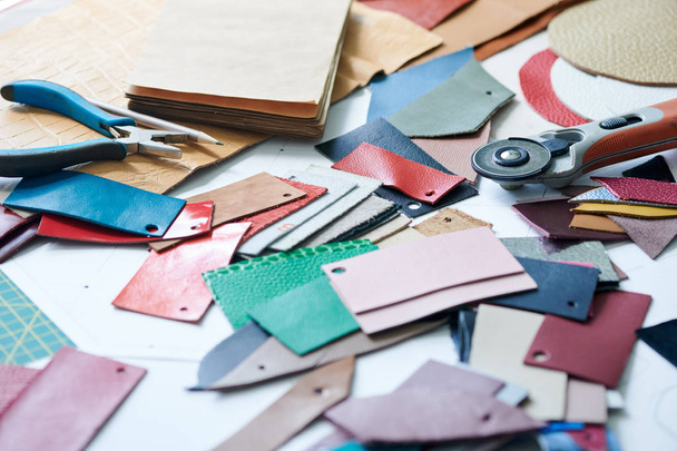 Close-up do local de trabalho com amostras de tecido de couro e ferramentas de trabalho em oficina
 - Foto, Imagem