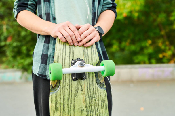 Close up of unrecognizable teenager holding longboard outdoors in skateboarding park, copy space - 写真・画像