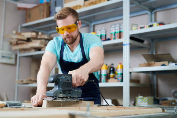 Artigiano in occhiali di sicurezza concentrato sul suo lavoro, sta lavorando con legno e utensili elettrici
 - Foto, immagini