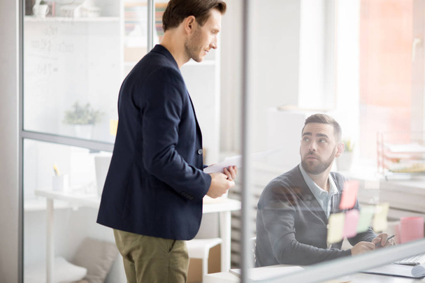 Retrato de vista lateral del gerente de negocios guapo hablando con el empleado en la oficina moderna, espacio de copia
 - Foto, Imagen