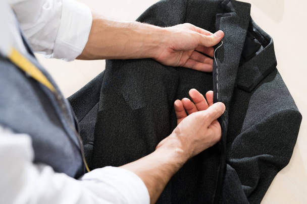 Boven uitzicht close-up van onherkenbaar mannelijke Tailor naaien klassieke jas in traditionele atelier studio, kopieer ruimte - Foto, afbeelding