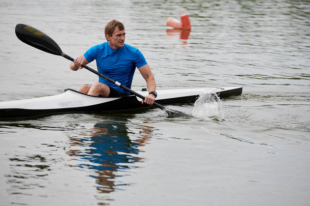 L'atleta che tiene un remo e galleggia in kayak sul lago
 - Foto, immagini