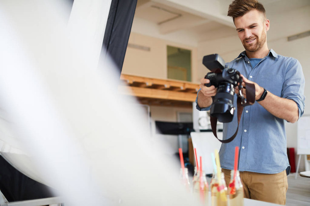 Cintura até retrato de sorrindo fotógrafo masculino atirando objetos e comida no estúdio de fotografia, espaço de cópia
 - Foto, Imagem