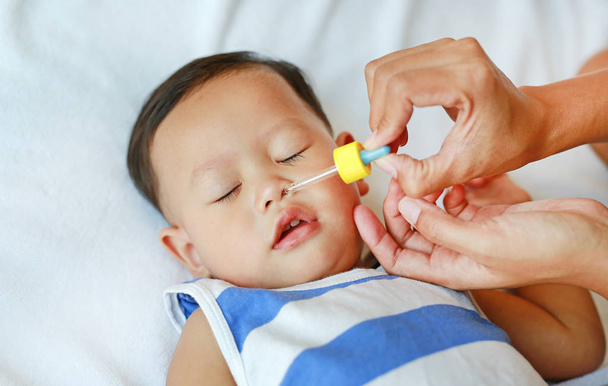 Mother dripping nasal drops for her son. Baby healthcare concept. - Fotografie, Obrázek