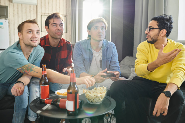 Группа молодых друзей проводит досуг с попкорном, пивом и видеоиграми
 - Фото, изображение