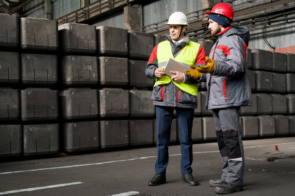 Портрет зрілого лідера, який носить хардхаус, дає вказівки працівникам, стоячи за бетонними блоками в майстерні, копіювати простір
 - Фото, зображення