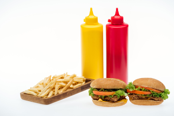 chicken burgers near french fries and bottles with mustard and ketchup isolated on white - Photo, Image