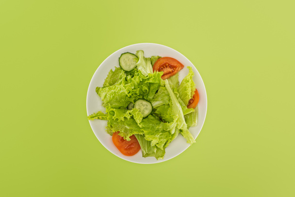 top view of chopped salad on white plate isolated on green - Photo, Image