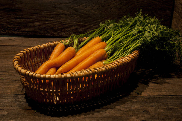 Zanahorias frescas con hojas verdes sobre fondo de madera vieja
  - Foto, Imagen