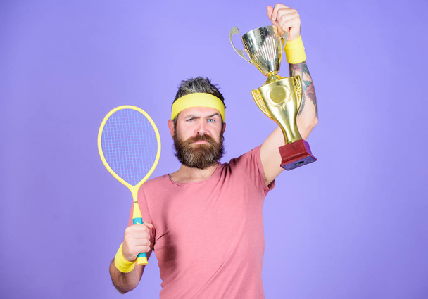 Success and achievement. Win tennis game. Tennis match winner. Achieved top. Tennis player win championship. Athlete hold tennis racket and golden goblet. Man bearded hipster wear sport outfit - Photo, Image