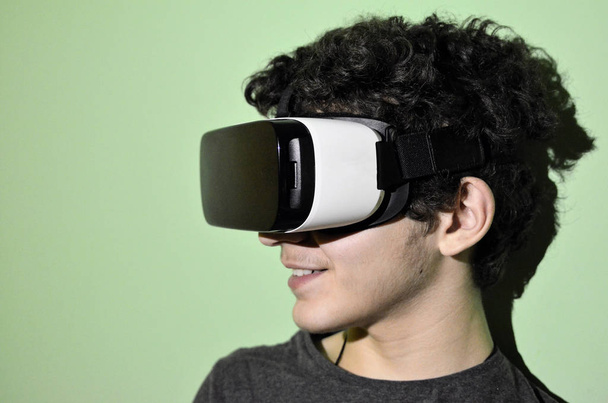 Nuori valkoihoinen poika käyttää VR 360 katsojaa huoneessaan.
 - Valokuva, kuva