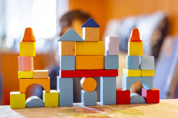 ein Kind spielt zu Hause mit farbigen Holzklötzen. Kind spielt und baut Gebäude und Türme mit farbigen Holzklötzen. - Foto, Bild