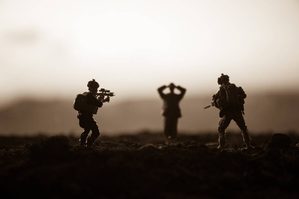Scena di battaglia. Silhouette militari scena di combattimento su sfondo cielo nebbia di guerra. Un soldato tedesco alzò le armi per arrendersi. Soldati giocattolo di plastica con pistole che prendono prigioniero il soldato nemico. Opera d'arte
 - Foto, immagini