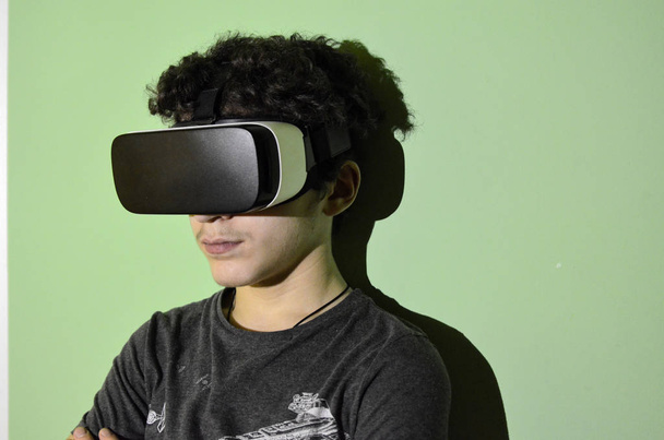 Молодой кавказский мальчик носит телезритель VR 360 в своей комнате
 - Фото, изображение
