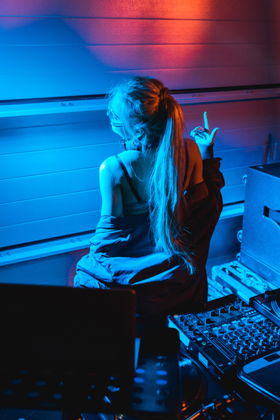  блондинка-ди-джей жестикулирует, стоя в ночном клубе
 - Фото, изображение