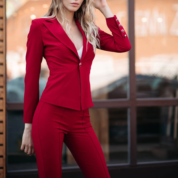 Elegant blonde woman in dark red suit with gold buttons. - Photo, Image