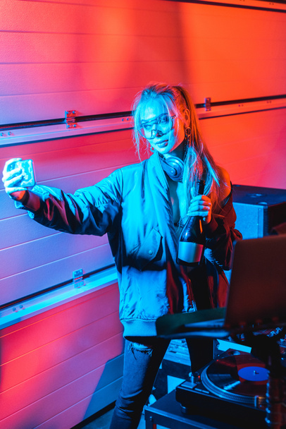 élégant blonde dj femme tenant bouteille et prendre selfie dans la boîte de nuit
 - Photo, image