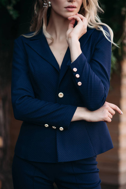 Elegant blonde woman in dark blue suit with gold buttons. - Photo, image