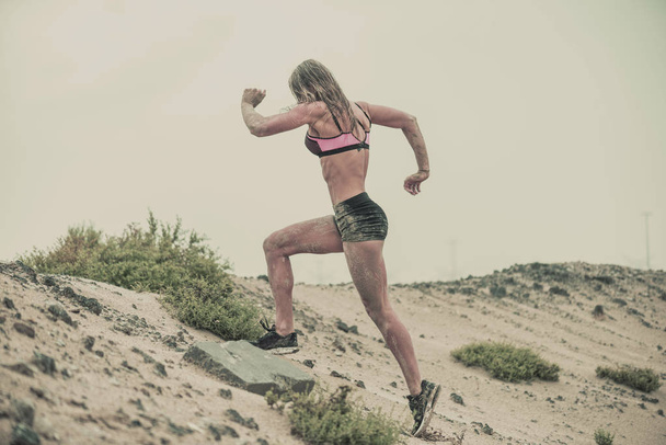 Сильные, здоровые спортсменки, покрытые грязью, бегущие по пересеченной местности с пустынным фоном в экстремальной спортивной гонке с грандиозным текстурированным финишем
 - Фото, изображение