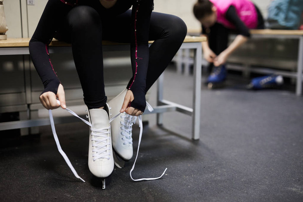 Portret van onherkenbaar meisje binden schaatsen schoen in de kleedkamer voor de oefening, kopieer ruimte - Foto, afbeelding