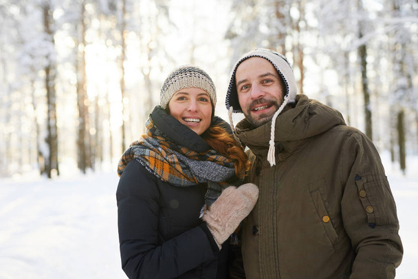Vyötärö ylös muotokuva onnellinen aikuinen pari talvella metsä katselee kameraa ja hymyilee, kopioi tilaa
 - Valokuva, kuva