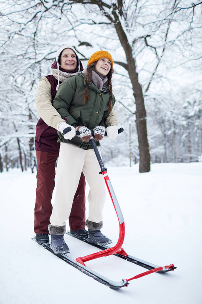 Full length portrait of happy young couple enjoying sleigh ride in beautiful winter forest - Photo, image