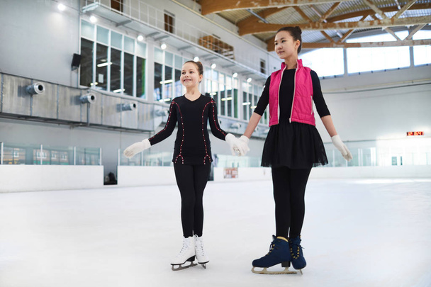 Retrato completo de dos chicas posando en una pista de patinaje cogidas de la mano, espacio para copiar
 - Foto, imagen