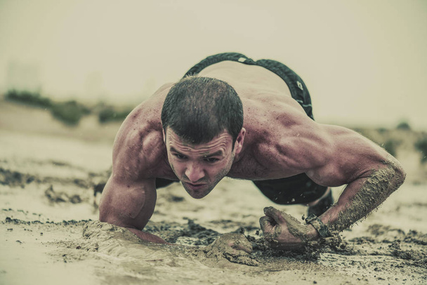 Portre güçlü, kaslı, atletik adamın ıslak, kirli çamurlu su birikintisi bir aşırı rekabetçi spor yağmurda içinde gezinme  - Fotoğraf, Görsel
