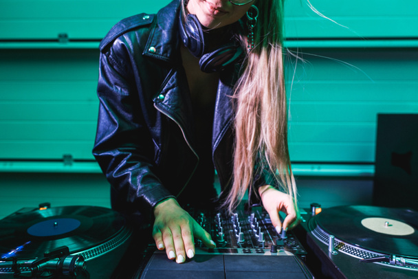 cropped view of blonde dj girl touching dj mixer in nightclub  - Photo, Image