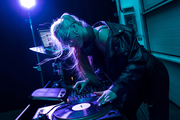 attractive blonde dj girl touching vinyl record in nightclub  - Photo, Image