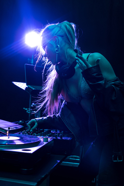 ξανθιά κομψό dj κορίτσι αγγίζει Μείκτης dj σε νυχτερινό κέντρο διασκέδασης  - Φωτογραφία, εικόνα